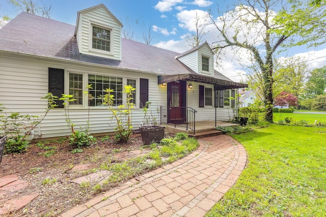 new england style home featuring a front yard and roof with shingles