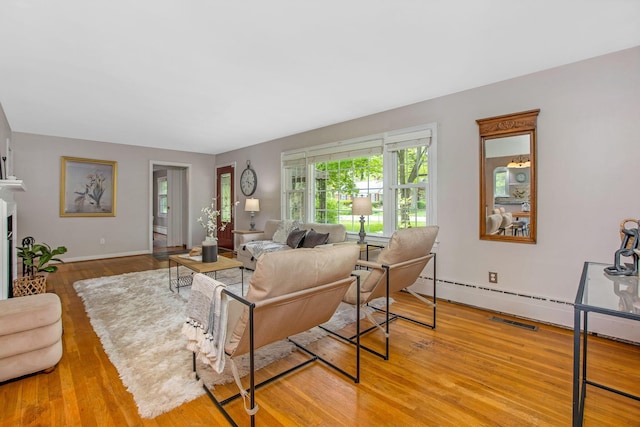 living room featuring wood finished floors, baseboards, and a baseboard heating unit