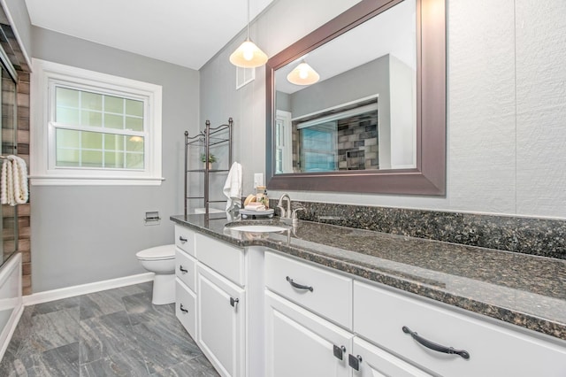 bathroom with marble look tile flooring, toilet, vanity, baseboards, and shower / bath combination with glass door