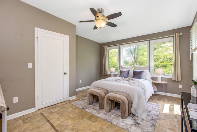 bedroom with baseboards, a ceiling fan, light stone finish floors, and lofted ceiling