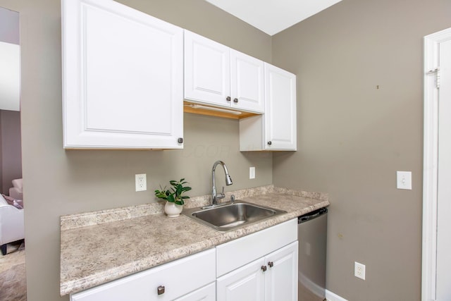 kitchen featuring a sink, stainless steel dishwasher, white cabinets, and light countertops