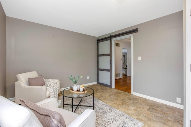 living room featuring a barn door, stone finish flooring, and baseboards