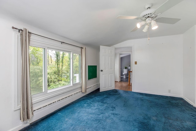 spare room featuring vaulted ceiling, dark carpet, a ceiling fan, baseboard heating, and baseboards