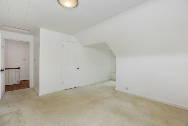 additional living space with carpet floors, lofted ceiling, and baseboards