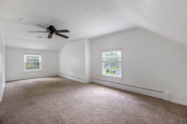 carpeted empty room featuring lofted ceiling, baseboard heating, a ceiling fan, and baseboards