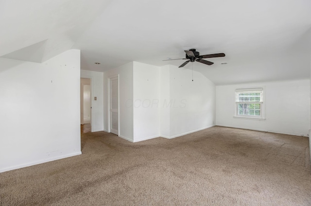 spare room featuring carpet, vaulted ceiling, ceiling fan, and baseboards