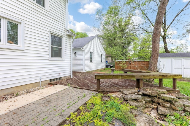view of yard featuring a deck, a storage shed, an outdoor structure, and a patio
