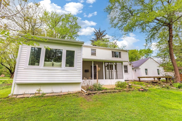rear view of house featuring a sunroom and a lawn