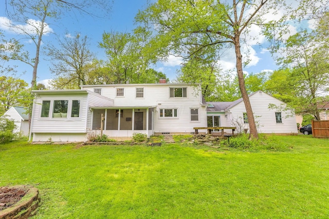 rear view of property with a sunroom, a lawn, and a chimney
