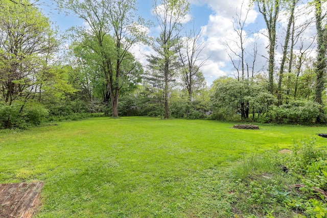 view of green lawn featuring an outdoor fire pit