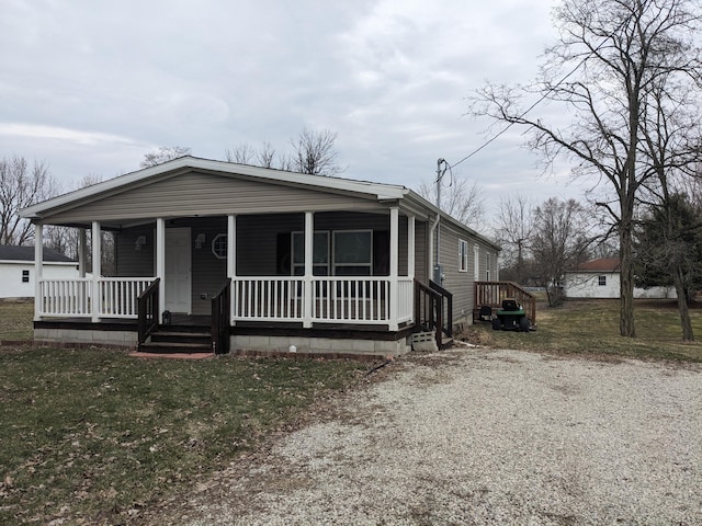 view of front of home featuring gravel driveway, a front lawn, and a porch