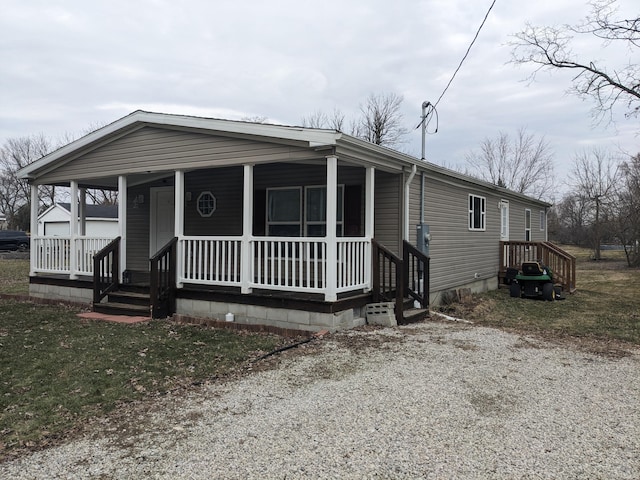 manufactured / mobile home featuring covered porch and gravel driveway