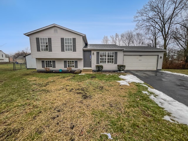 split level home with aphalt driveway, a front yard, entry steps, fence, and a garage