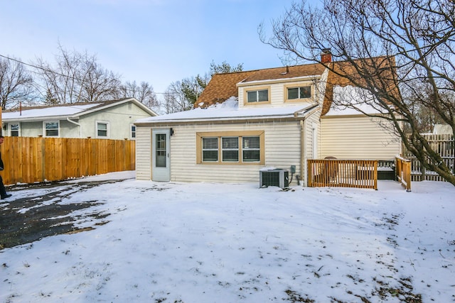 snow covered house with a deck and central AC unit