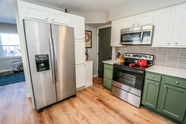 kitchen featuring appliances with stainless steel finishes, tasteful backsplash, light hardwood / wood-style flooring, and green cabinets