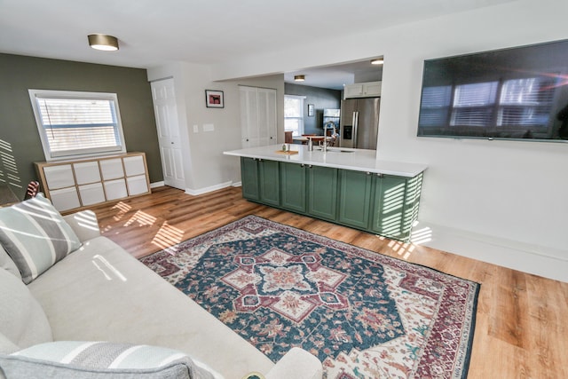 living room featuring light wood-type flooring, a wealth of natural light, and sink