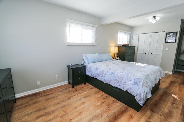 bedroom featuring beam ceiling, a closet, and hardwood / wood-style floors