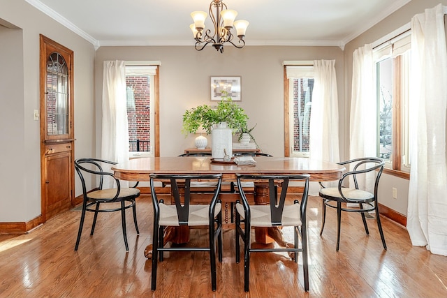 dining room featuring an inviting chandelier, light wood-type flooring, plenty of natural light, and crown molding