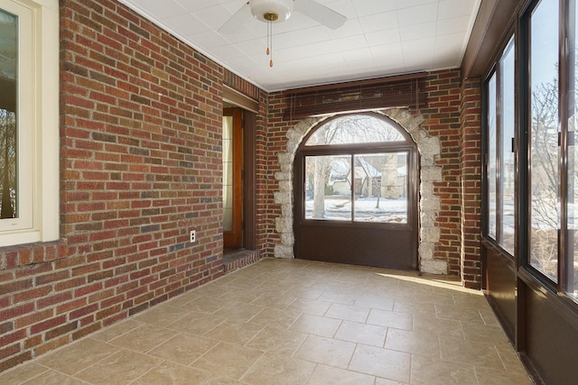 foyer entrance featuring ceiling fan and brick wall