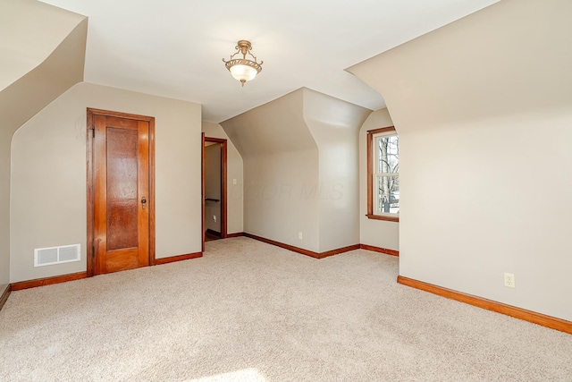 bonus room with light carpet and vaulted ceiling