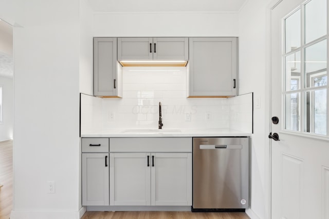 kitchen with light hardwood / wood-style flooring, sink, dishwasher, gray cabinets, and decorative backsplash