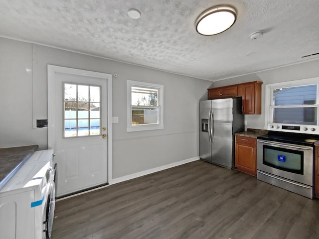 kitchen featuring independent washer and dryer, stainless steel appliances, a textured ceiling, and dark wood-type flooring