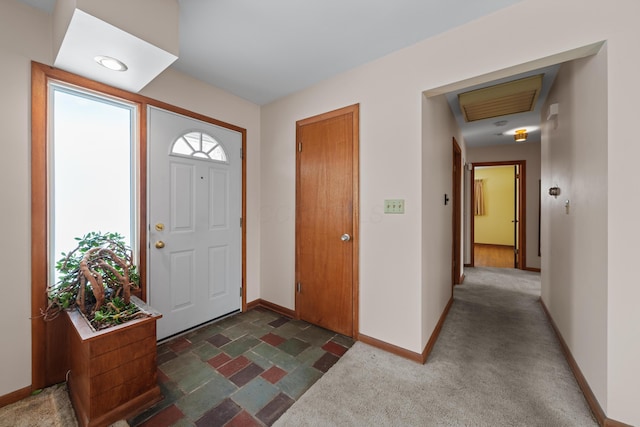 entryway with stone finish floor, dark carpet, visible vents, and baseboards