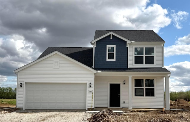 view of front facade featuring covered porch, gravel driveway, a shingled roof, and an attached garage