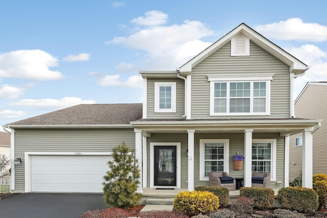 traditional-style home featuring a porch, roof with shingles, driveway, and a garage