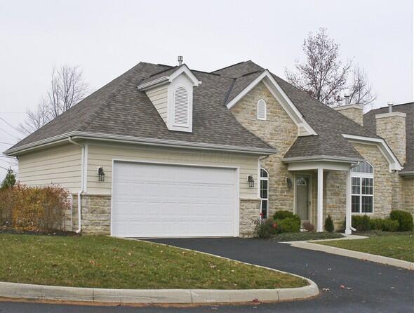 view of front facade featuring a shingled roof, an attached garage, stone siding, driveway, and a front lawn