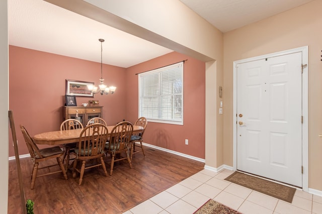 dining area with light tile patterned floors, baseboards, and a notable chandelier