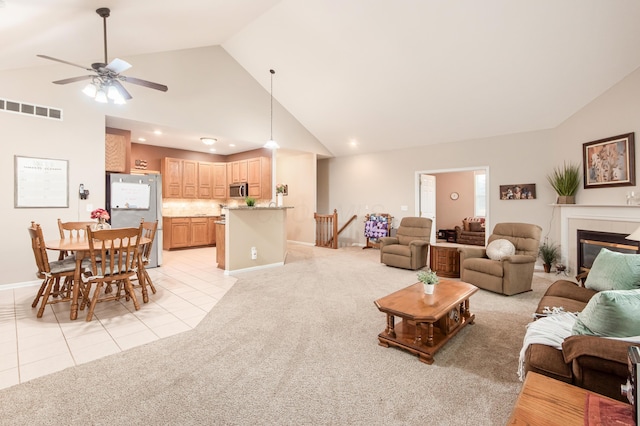 living area featuring light tile patterned floors, a glass covered fireplace, visible vents, and light colored carpet