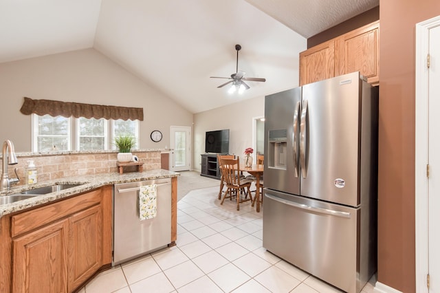 kitchen with lofted ceiling, ceiling fan, light tile patterned flooring, stainless steel appliances, and a sink