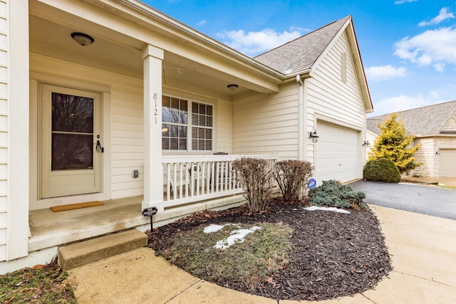 view of front of home featuring covered porch, aphalt driveway, an attached garage, and a shingled roof