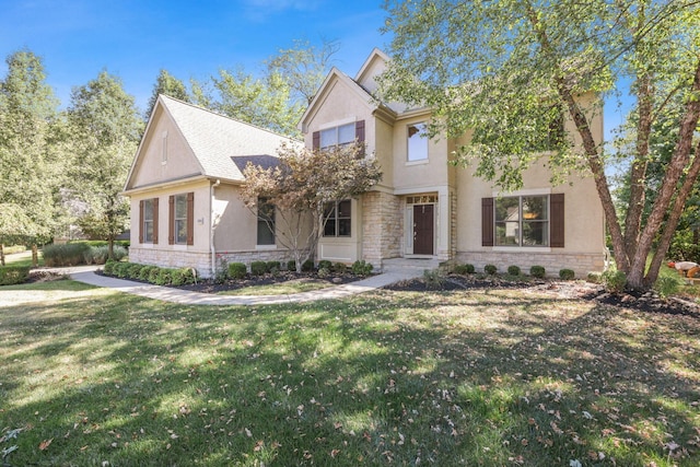 view of front facade with stone siding, a front yard, and stucco siding