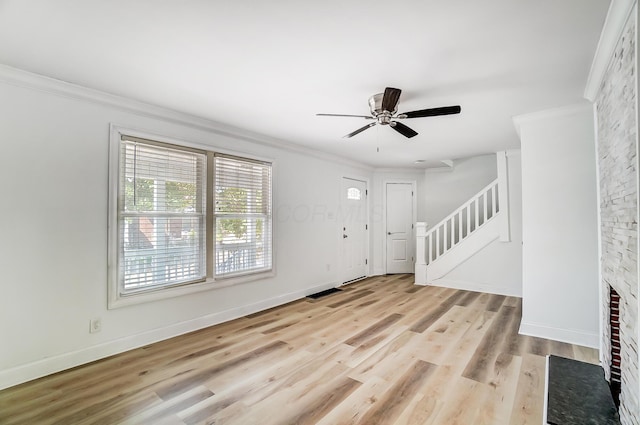 foyer featuring light hardwood / wood-style floors, ceiling fan, a large fireplace, and ornamental molding