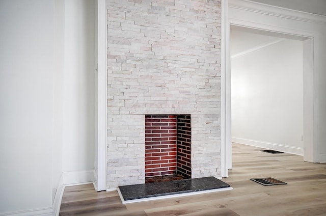 interior details featuring a fireplace, ornamental molding, and wood-type flooring