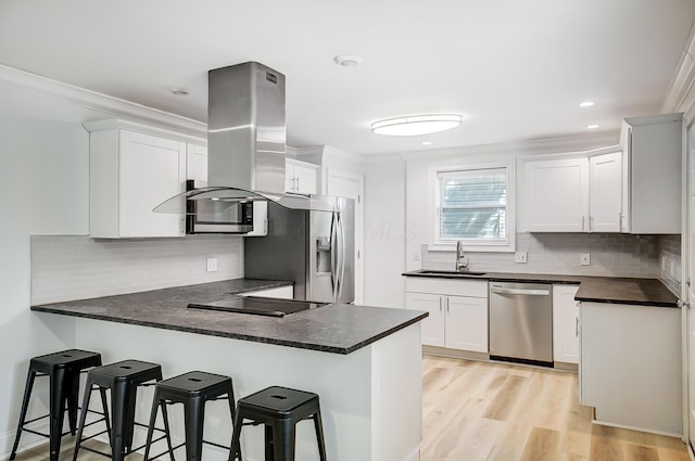 kitchen with white cabinetry, kitchen peninsula, sink, appliances with stainless steel finishes, and island exhaust hood