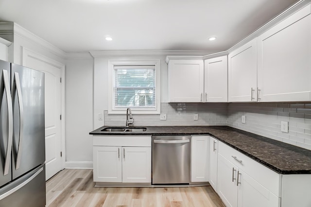 kitchen featuring sink, dark stone counters, appliances with stainless steel finishes, white cabinets, and decorative backsplash