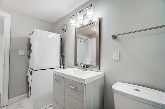 bathroom featuring toilet, stacked washer / drying machine, and vanity