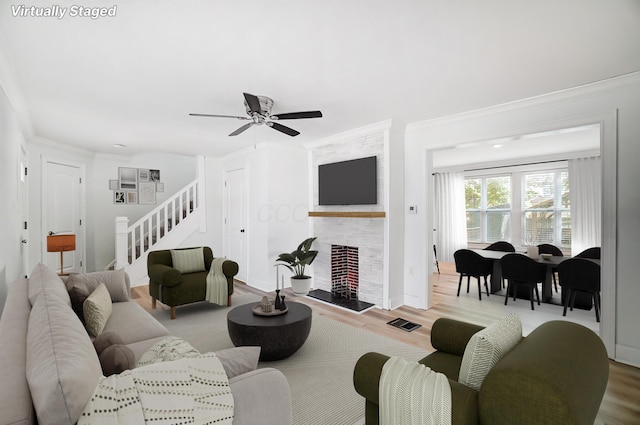 living room with a fireplace, ceiling fan, light hardwood / wood-style floors, and crown molding