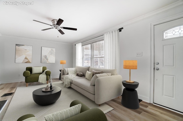 living room with ceiling fan, ornamental molding, and light hardwood / wood-style floors