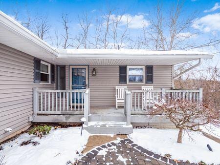 snow covered property entrance with a porch