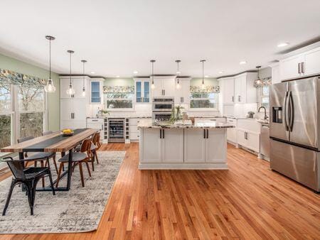 kitchen with light stone counters, a kitchen island, white cabinetry, appliances with stainless steel finishes, and pendant lighting