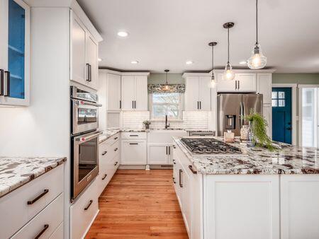 kitchen with stainless steel appliances, hanging light fixtures, light wood-style flooring, and white cabinetry