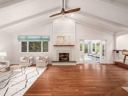 unfurnished living room with a large fireplace, lofted ceiling with beams, and wood finished floors