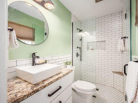 full bath with toilet, a stall shower, vanity, and tile walls