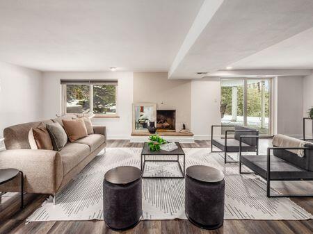 living area with a healthy amount of sunlight, a fireplace with raised hearth, baseboards, and wood finished floors