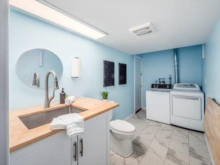 bathroom with marble finish floor, a sink, toilet, and separate washer and dryer