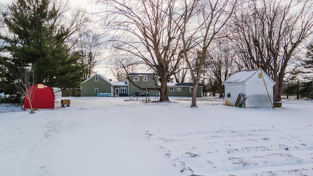 yard layered in snow featuring a storage shed and an outdoor structure